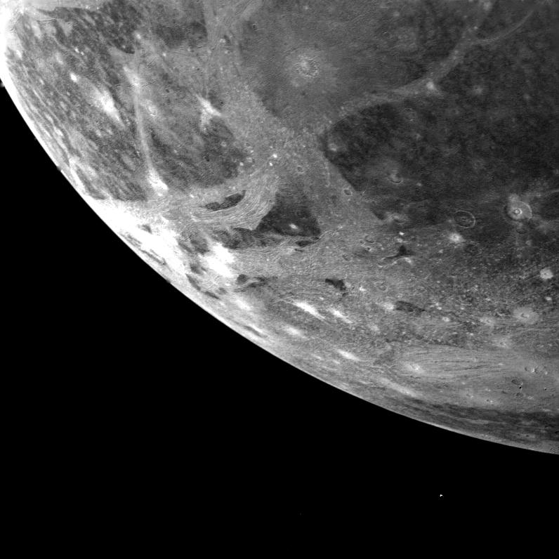 The curved edge of Ganymede, with light grooves and dark patches