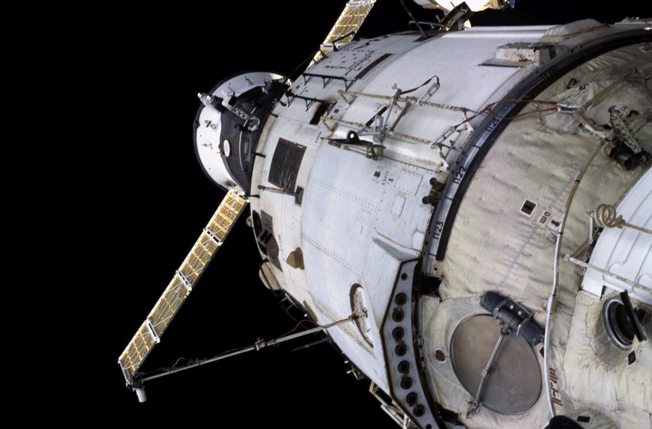 A close view of white space-station modules and a gold solar panel in orbit